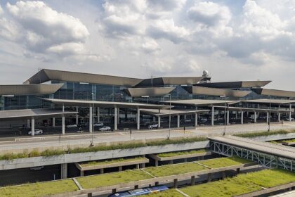 The outside of São Paulo International Airport (GRU) terminal 3, the international departure terminal. The sky is cloudy and the building is mostly grey but covered by windows.