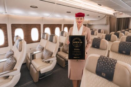 Flight attendant holding APEX award onboard an aircraft.