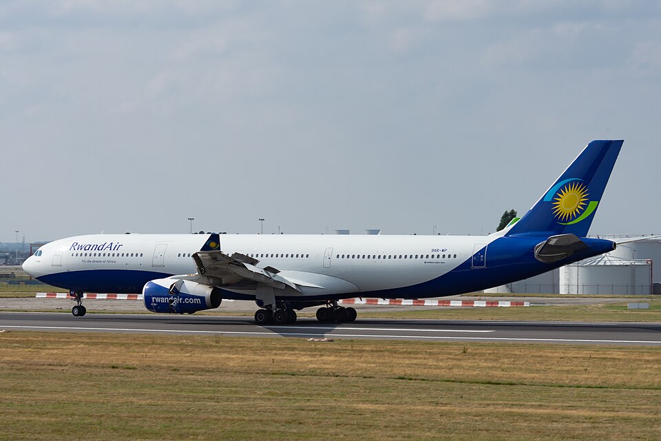 A RwandAir A330 after landing at Brussels International Airport. The sky is mostly grey and the runway is surrounded by grass. The livery is white with a blue tail.
