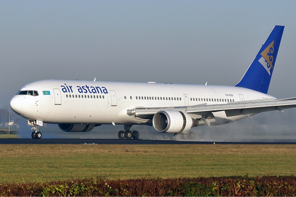 Air Astana Boeing 767-300 on the runway. Grass can be seen in the foreground and the sky is a cloudless blue