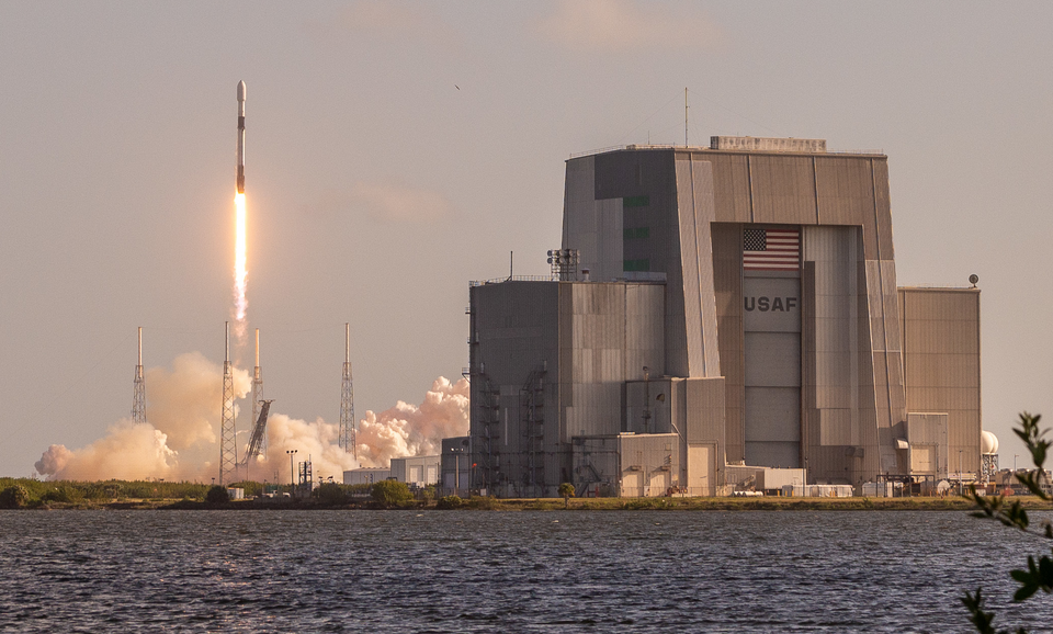 The Solid Motor Assembly Building (SMAB) as taken from its southern side. In the background is Space Launch Complex 40 (SLC-40), launching a Falcon 9 carrying Starlink 4-10.