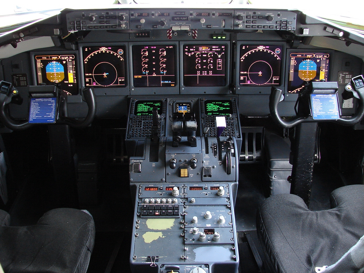 The cockpit of a B717. There are two seats for the pilots, a few colourful screens and metal buttons.