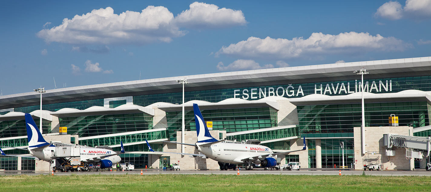 The exterior at Esenboga Airport, showing planes at terminals as people board.