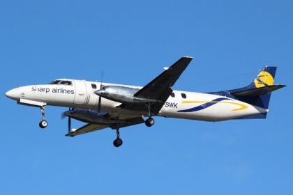 A Sharp Airlines Fairchild SA227-DC Metro 23 flying under a blue sky. The aircraft's livery is mostly white with a dark blue tail with yellow accents.