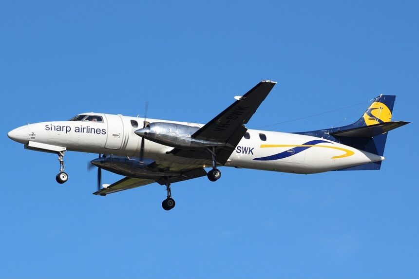 A Sharp Airlines Fairchild SA227-DC Metro 23 flying under a blue sky. The aircraft's livery is mostly white with a dark blue tail with yellow accents.