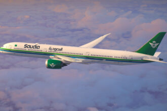 A Saudia Airlines jet in front of a cloudy sky.