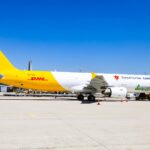 A DHL branded SmartLynx jet sat on a runway on a sunny day.