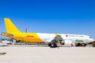 A DHL branded SmartLynx jet sat on a runway on a sunny day.