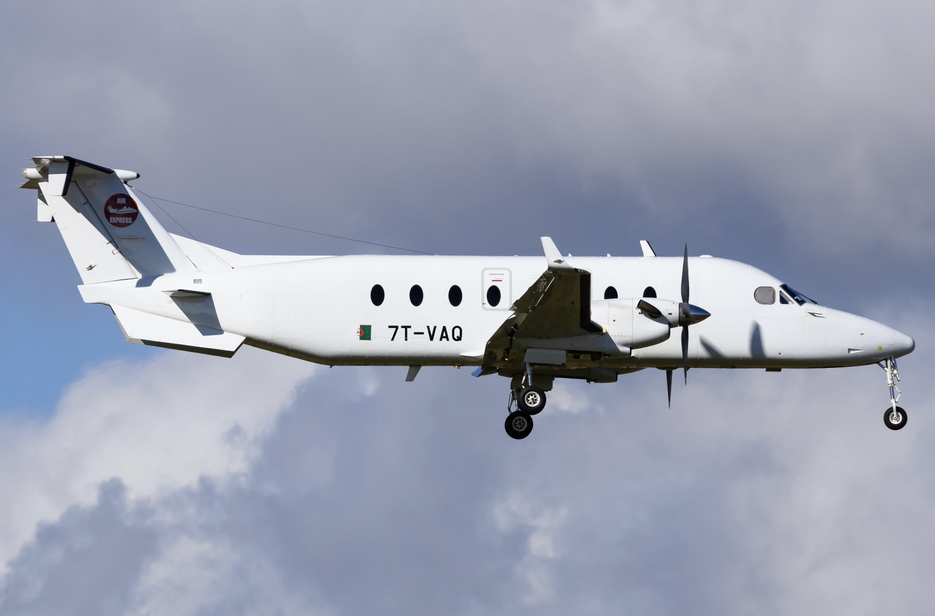 An Air Express Algeria Beechcraft 1900D plane in front of a cloudy sky.
