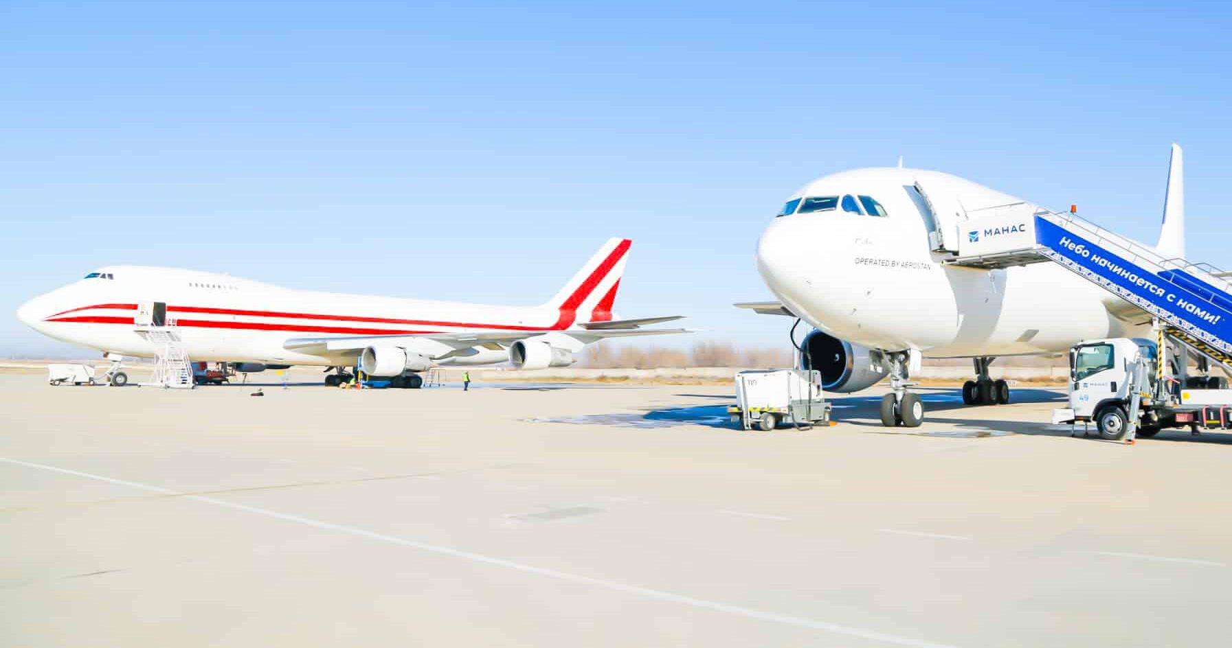 Two Aerostan jets on a runway in front of a clear sky. One is plain white, and the other has two red stripes running down its flank.