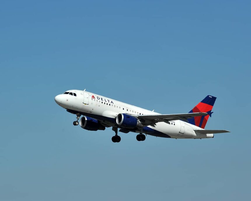 A Delta Air Lines Airbus A319 flying upwards in front of a clear blue sky.