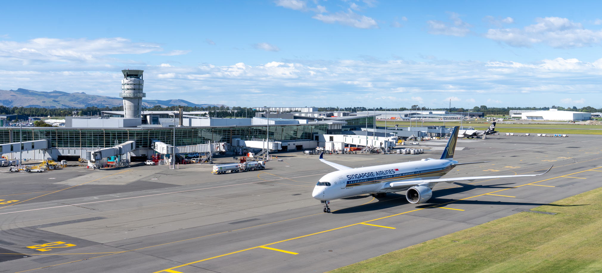 A Singapore Airlines jet on the runway at Christchurch Airport on a sunny day with some clouds in the sky.