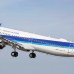 An Airbus jet from All Nippon Airways flying upwards in front of a clear blue sky.