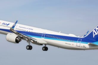 An Airbus jet from All Nippon Airways flying upwards in front of a clear blue sky.
