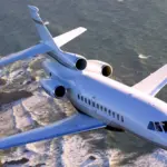 A Dassault Falcon 900EX jet flying over a rocky coastline, with a choppy sea behind it.