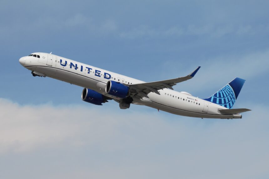 A United Airlines Airbus A321neo is pictured climbing through a cloudy blue sky after take-off.