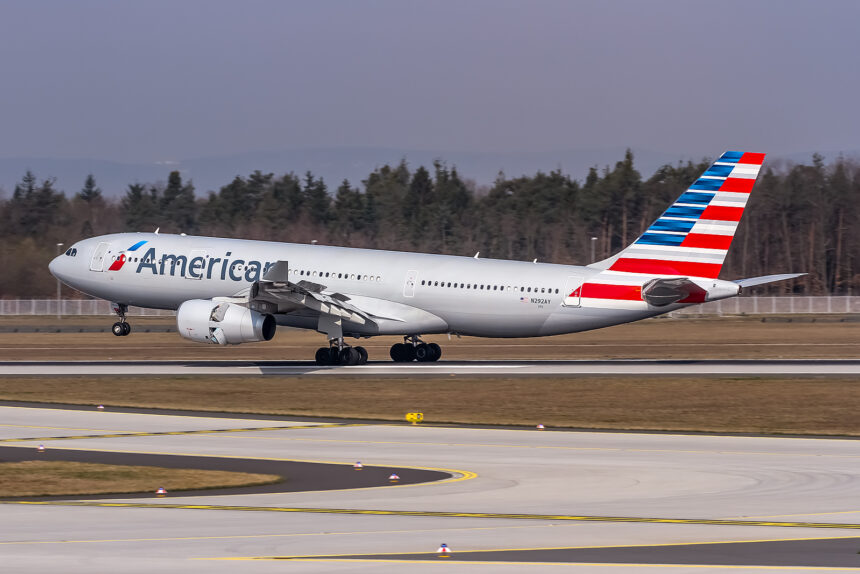 An American Airlines Airbus A330-243 aircraft taking off from the runway. Trees and a grey/blue sky in the background.