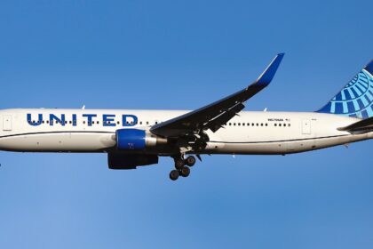A United Airlines aircraft flying in the blue sky, no clouds, with the landing gear out.