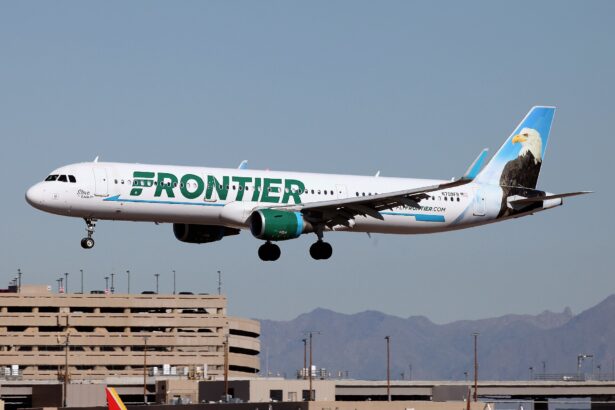 A Frontier Airlines Airbus plane coming in to land at an airport, its landing gear is out. White and green livery.