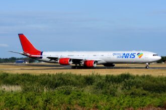 A European Cargo aircraft in NHS-branded livery taxis on a runway at an airport in the United Kingdom. The aircraft was used to transport personal protective equipment and COVID-19 test kits during the pandemic.