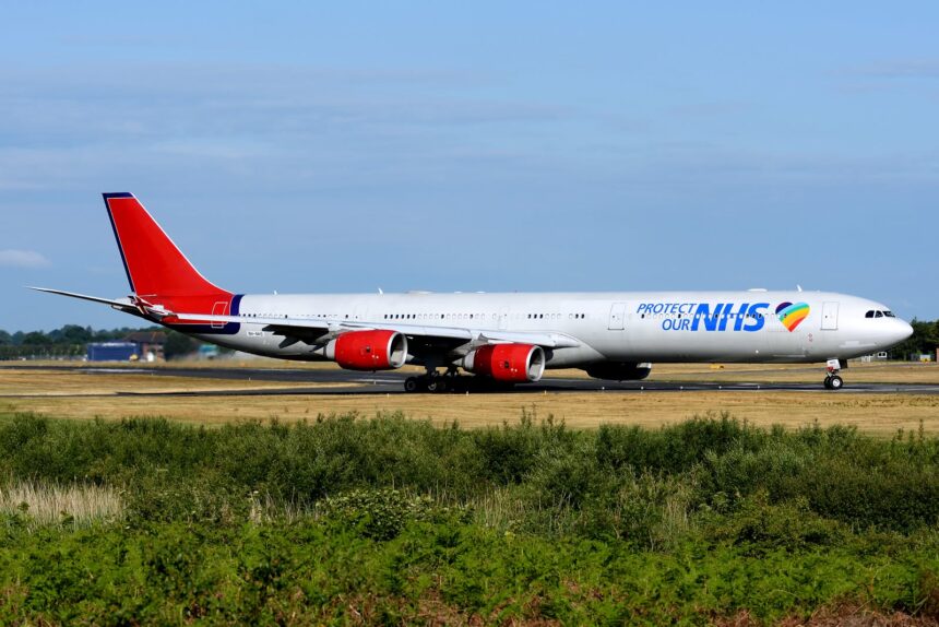 A European Cargo aircraft in NHS-branded livery taxis on a runway at an airport in the United Kingdom. The aircraft was used to transport personal protective equipment and COVID-19 test kits during the pandemic.