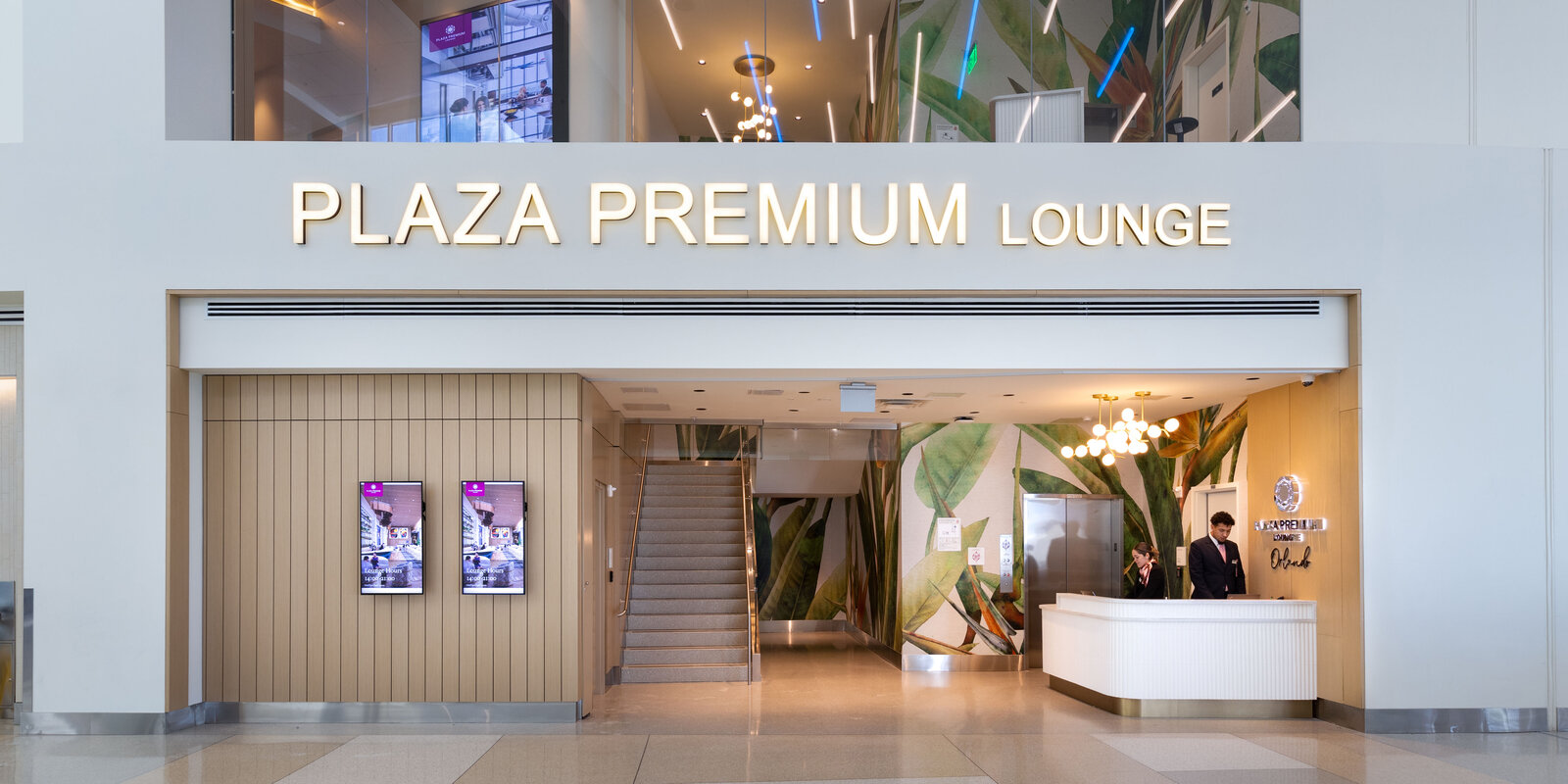 The façade of Plaza Premium Lounge in Orlando Airport, featuring a small reception on the right side and stairs right at the front