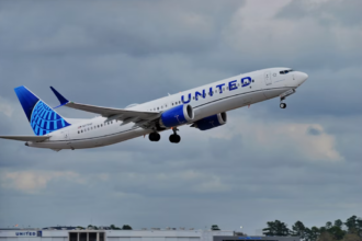 A large blue and white jetliner flying through a cloudy sky
