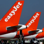 Three orange and white EasyJet jetliners sitting on a runway
