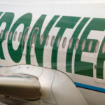 A close-up view of the side of a white and green Frontier jetliner