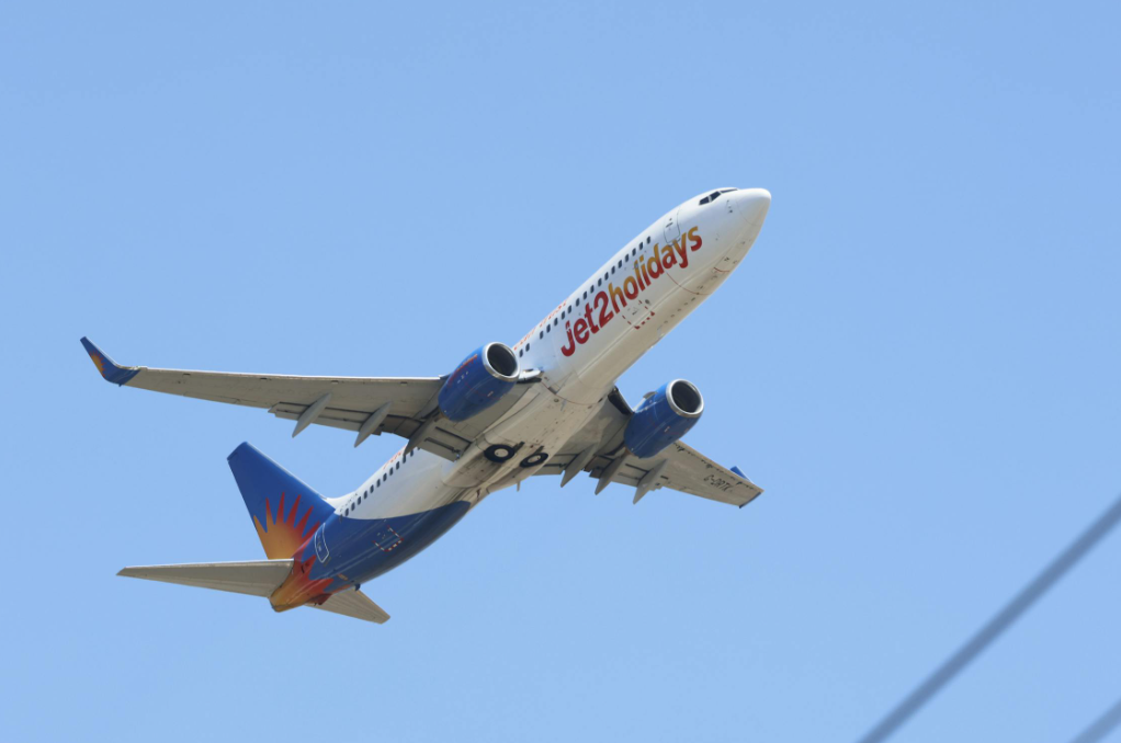 The underneath of a white and blue Jet2 aircraft flying in the sky