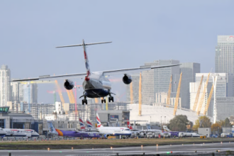 A plane landing at an airport with tall buildings in the background