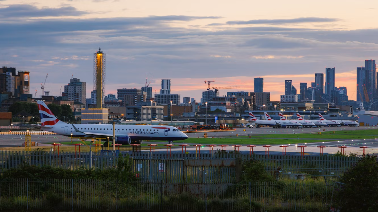 A large jetliner sitting on an airport runway with a sunset