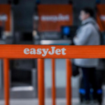 An orange barrier with white text reading 'EasyJet' on it and a person standing in the background.