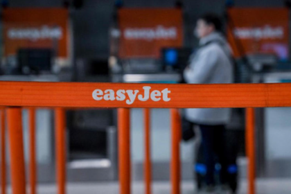 An orange barrier with white text reading 'EasyJet' on it and a person standing in the background.