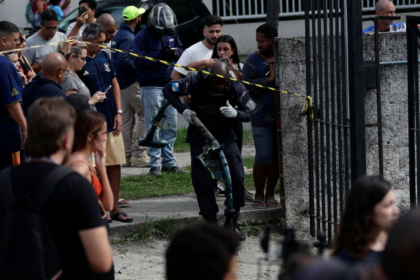A crowd of people standing beside a concrete wall with caution tape in front of it