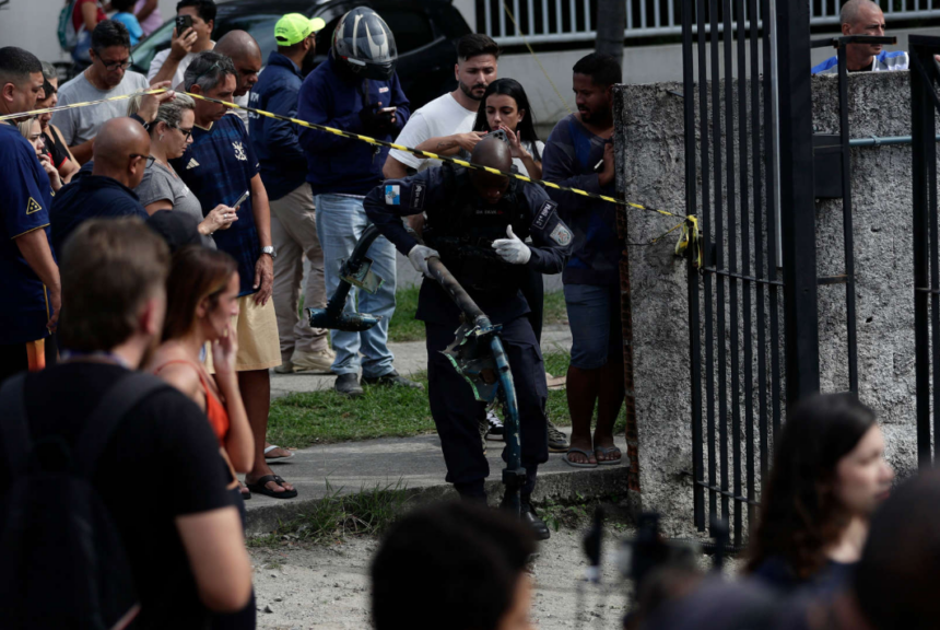 A crowd of people standing beside a concrete wall with caution tape in front of it