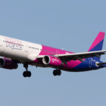 A large pink, white and blue jetliner flying in a blue sky
