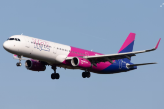 A large pink, white and blue jetliner flying in a blue sky
