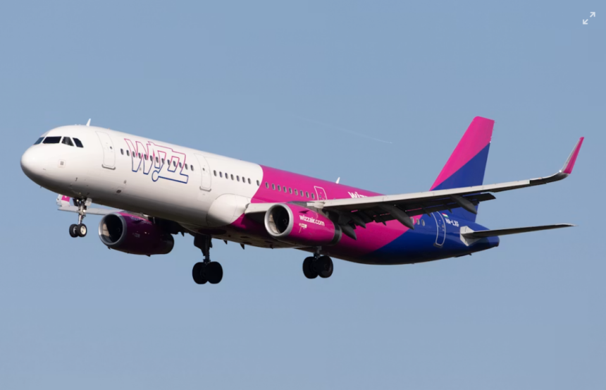 A large pink, white and blue jetliner flying in a blue sky