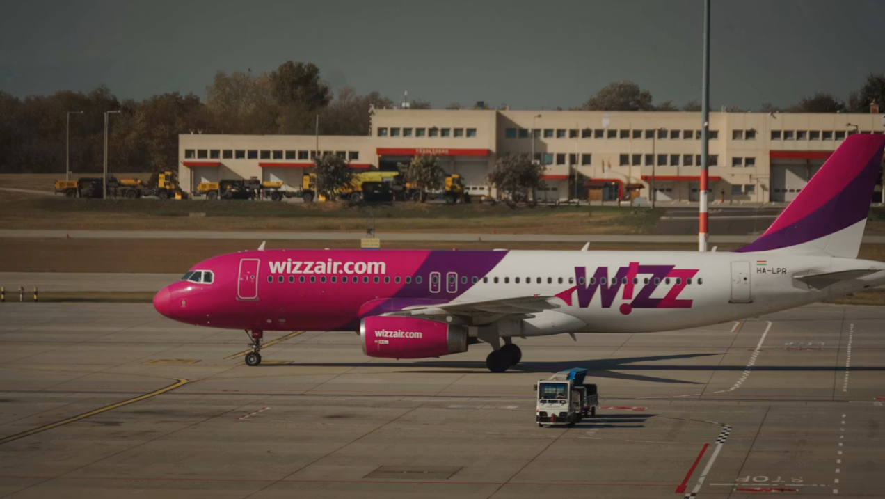 A pink and white passenger plane at the airport during daytime