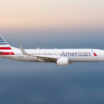A large white jetliner flying through a cloudy sky.