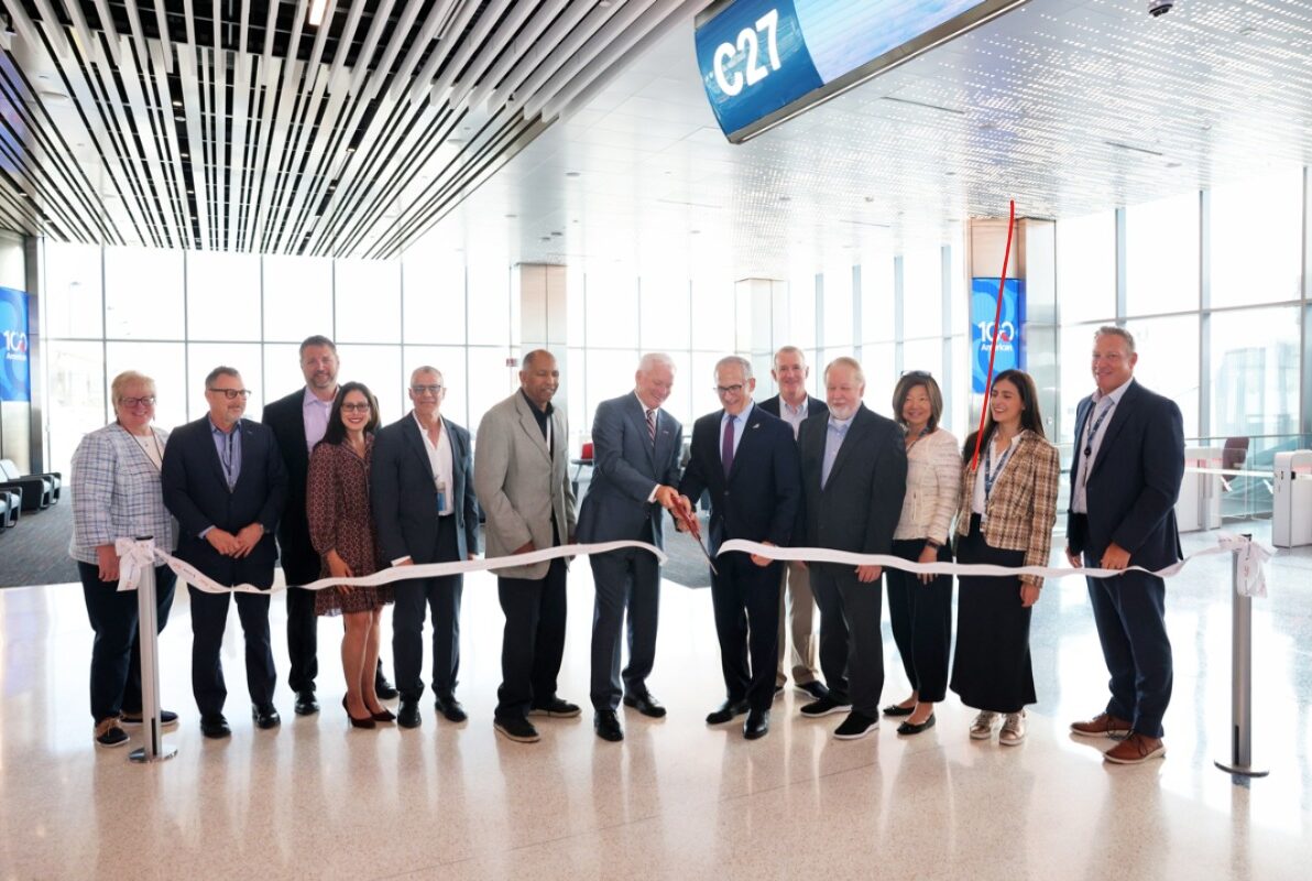 Image shows a number of people at a ribbon cutting ceremony of new Terminal C Pier at Dallas Fort Worth Airport