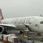 Virgin Atlantic Airbus A350-1000 on runway, being refulled, with palletts and workers surrounding
