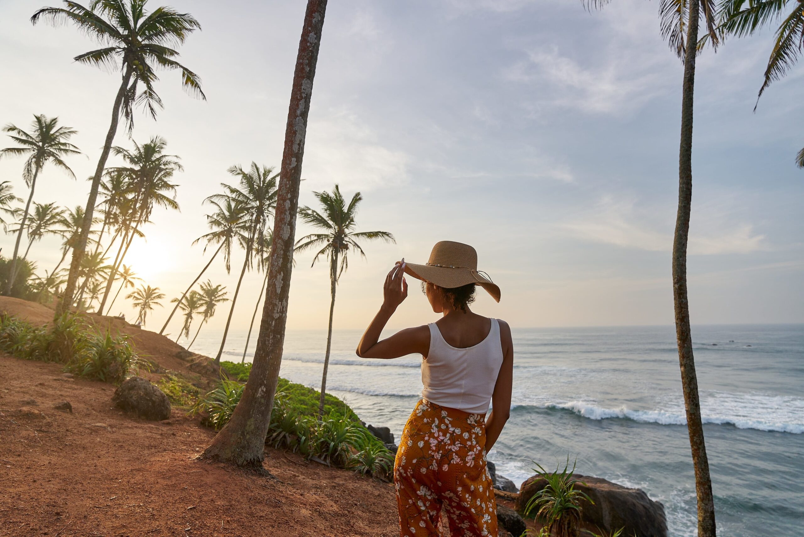 A lady stands on a beach surrounded by palm trees in Sri Lanka 