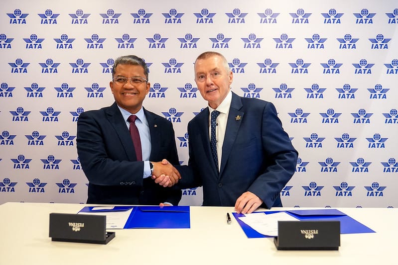 Image shows Capt. Nasaruddin A. Bakar, President and Group CEO of MAG, and Willie Walsh, Director General of the International Air Transport Association (IATA) shaking hands at a desk with IATA logos on the wall behind them