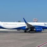 IndiGo Airbus A321neo (VT-IME) on the apron with an air traffic control tower visible in the background.