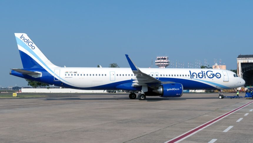 IndiGo Airbus A321neo (VT-IME) on the apron with an air traffic control tower visible in the background.