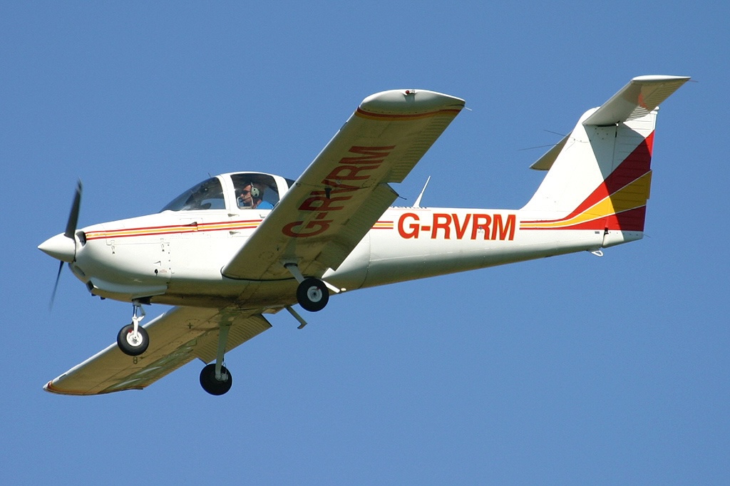 Side view of Ravenair's Piper PA-138-112 Tomahawk (registration G‑RVRM) mid-flight with its landing gear extended.