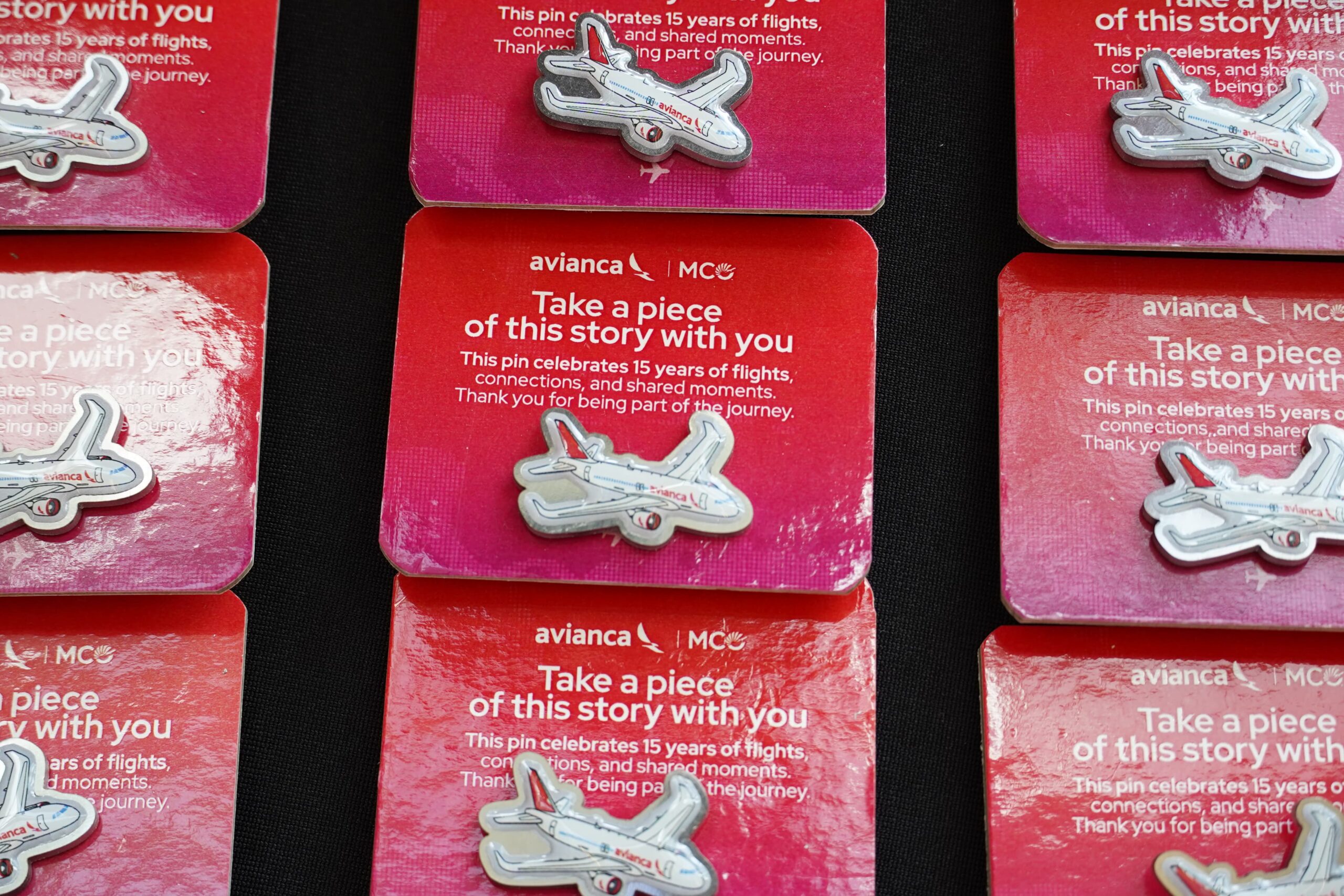 Avianca X MCO pin badges celebrating 15 years of operations from Orlando presented on a black surface. nine badges in total