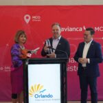 Avianca and MCO officials holding a trophy and model aircraft in front of banners celebrating 15 years of operations